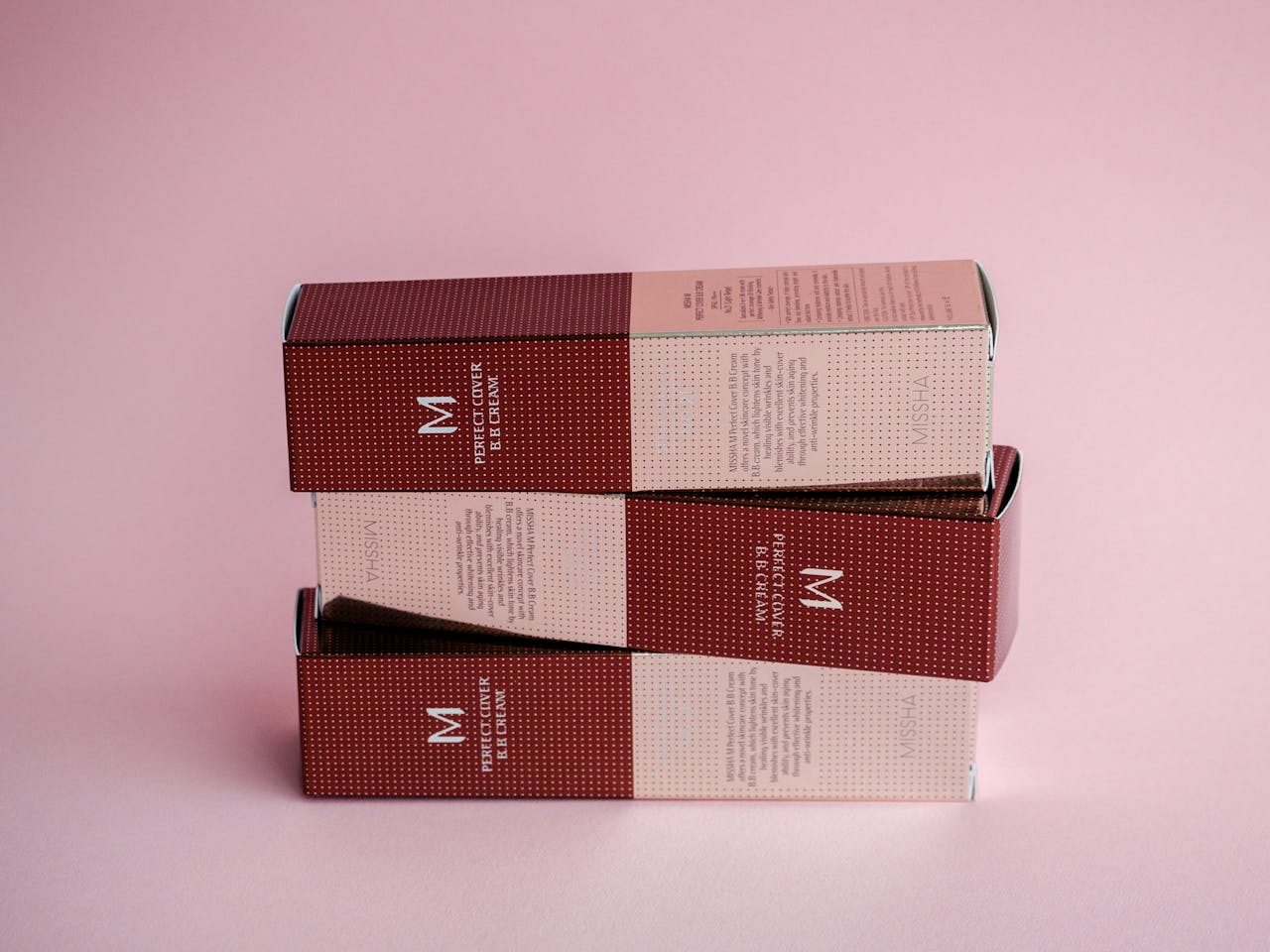 Sophisticated display of luxury cosmetic boxes against a pastel pink backdrop.