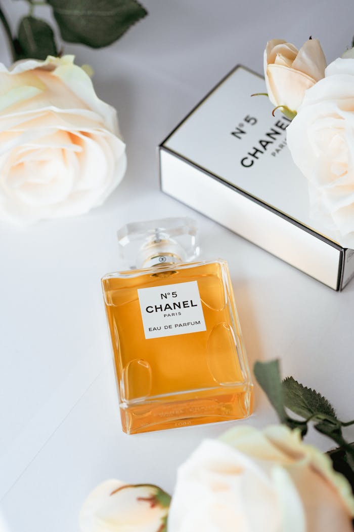 Elegant Chanel No. 5 perfume bottle surrounded by soft white roses, capturing luxury and fragrance.