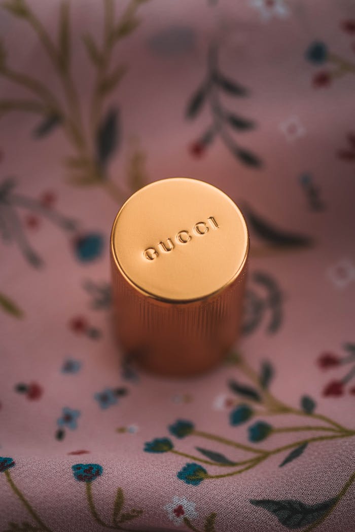 Elegant close-up of a Gucci perfume cap resting on a floral pattern fabric.